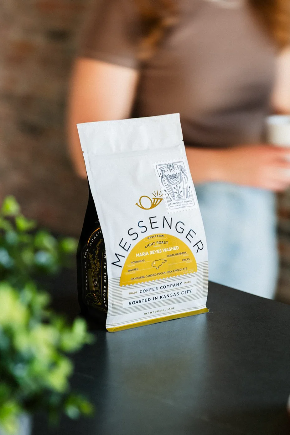 Messenger Coffee Single Origin Coffee on a black counter top with person in background.
